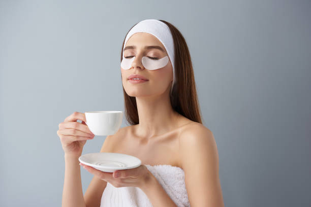 istock Charming young woman using under-eye patches and enjoying hot drink 1126442999