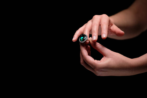 Studio shot black background female hands trying on the big emerald ring