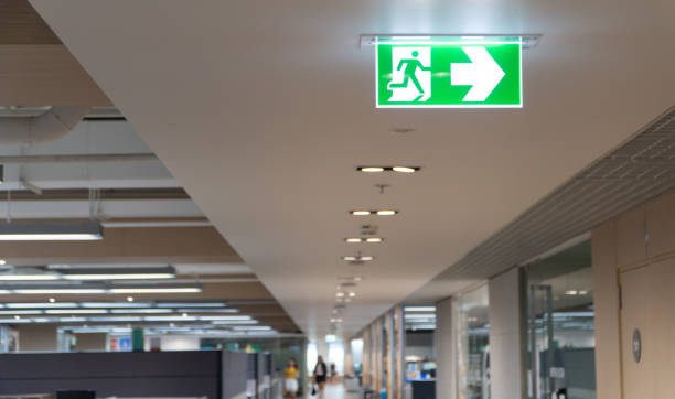 istock Green fire escape sign hang on the ceiling in the office. 1126445230
