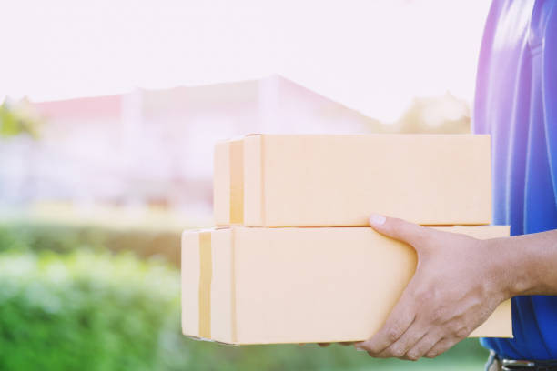 istock parcel delivery man of a package through a service. and close up hand customer accepting a delivery of boxes from delivery man postal send direct to home. 1126446697