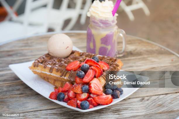 Blegium Waffles Topped With Strawberry Blueberry Ice Cream Ball And Chocolate Sauce Served With Milkshake On Wooden Table On A Hot Summer Day Date Stock Photo - Download Image Now