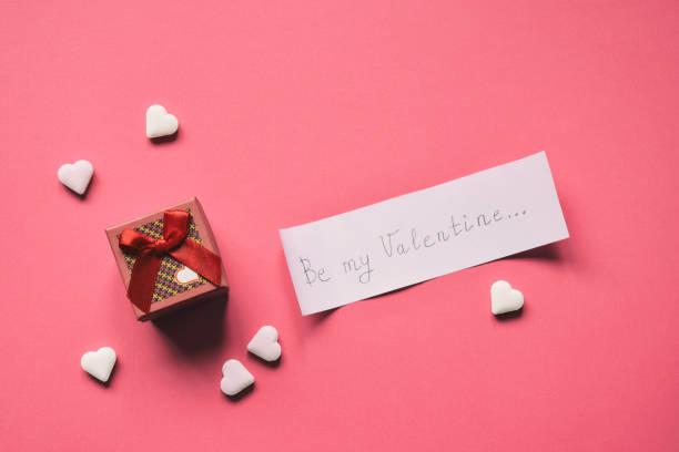 istock Small present box and paper with text be my Valentine on pink background. Valentine's Day Gift or greeting card concept. 1126451124