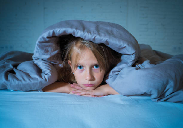 carina bambina caucasica sdraiata a letto che copre la testa con la coperta che si sente esausta e insonne che soffre di insonnia depressione stress nei bambini concetto di disturbi emotivi e del sonno. - dreams child sleeping little girls foto e immagini stock