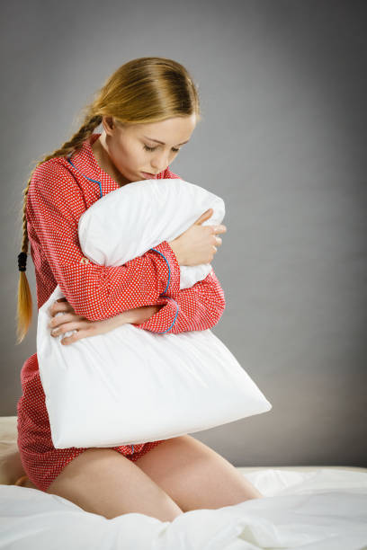 istock Sad depressed girl in bed gripping pillow 1126459255
