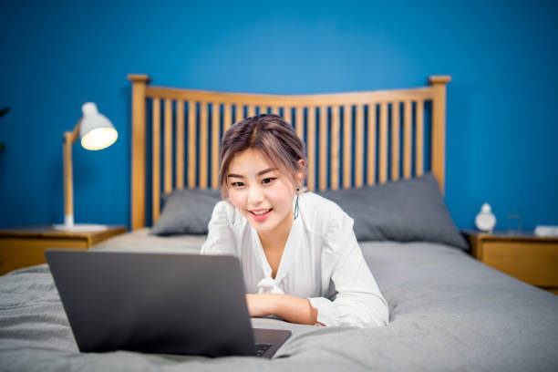 istock Young woman using a laptop on her bed 1126463250