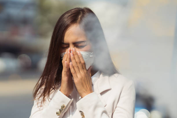 Asian woman are going to work.she wears N95 mask.prevent PM2.5 dust and smog.she is coughing stock photo