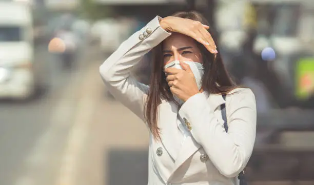Asian woman are going to work.she wears N95 mask.prevent PM2.5 dust and smog.she is coughing