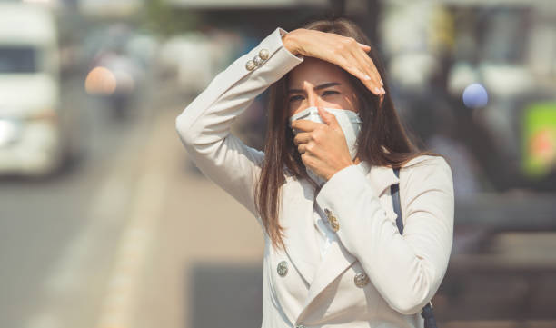 asian woman are going to work.she wears n95 mask.prevent pm2.5 dust and smog.she is coughing - poluição do ar imagens e fotografias de stock