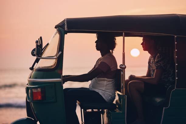 Journey by tuk tuk Driver and passenger are traveling by tuk tuk taxi against sea at sunset in Sri Lanka. taxi sri lanka stock pictures, royalty-free photos & images