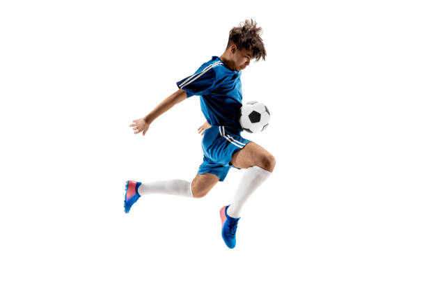 niño con balón de fútbol haciendo patada voladora - child lifestyles isolated blue fotografías e imágenes de stock