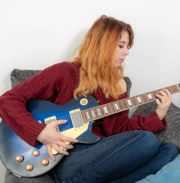 istock Young woman practising the guitar on the sofa 1126477062
