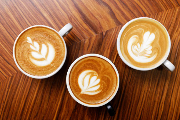 Three cups of cappuccino coffee on a wooden table