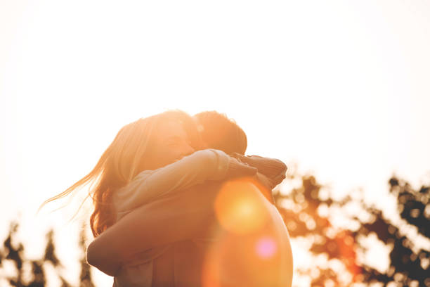 Mid adult couple hugging outdoors at sunny day.