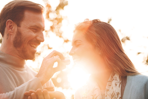 Mid adult couple sharing macaroons outdoors at sunny day.