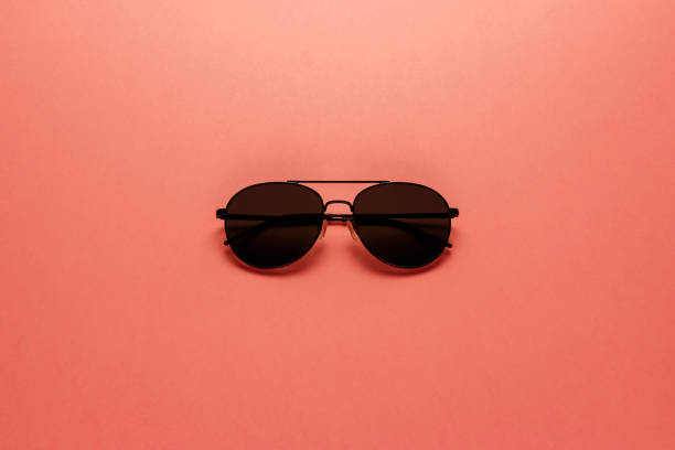 istock Black sunglasses on coral background. Top view. Flat lay. Copy space. Minimal style with colorful paper backdrop. Summer is coming concept. Living Coral color of the Year 2019 1126485138