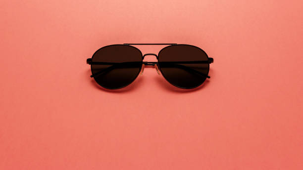 istock Black sunglasses on coral background. Top view. Flat lay. Copy space. New minimal creative concept. Summer is coming concept. Living Coral color of the Year 2019 1126485157