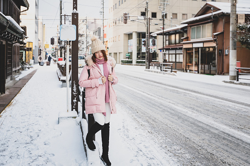 Beautiful woman standing on the side of the road with white snow winter at Takayama city, Japan