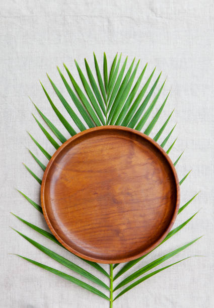 istock Wooden plate with palm leaf on natural linen textile background. Copy space. Top view. 1126485493