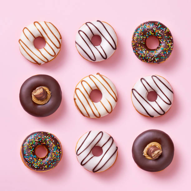 donuts-auswahl auf einem rosa hintergrund von oben gesehen. ansicht von oben - sprinkles isolated white multi colored stock-fotos und bilder