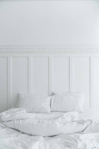 istock Cozy bedroom setting with two pillows and messy blanket and classic element install on white painted wall / modern classice style / luxury concept / interior 1126488428