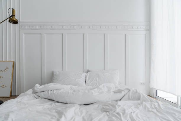 istock Cozy bedroom setting with two pillows and messy blanket and classic element install on white painted wall / modern classice style / luxury concept / interior 1126488438