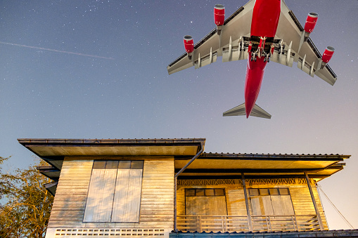 Big passenger plane over wooden house in countryside at night