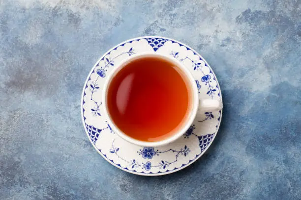 Photo of Cup of tea on a blue stone background. Copy space. Top view.