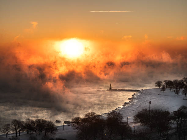 A beautiful aerial photograph of a sunrise over the steam rising from Lake Michigan during the polar vortex of winter 2019 with subzero temperatures at the snow covered Foster Beach. stock photo