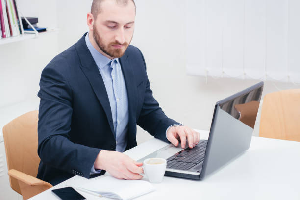 istock Elegant business man in a suit sitting in the office and using  laptop computer . 1126492127