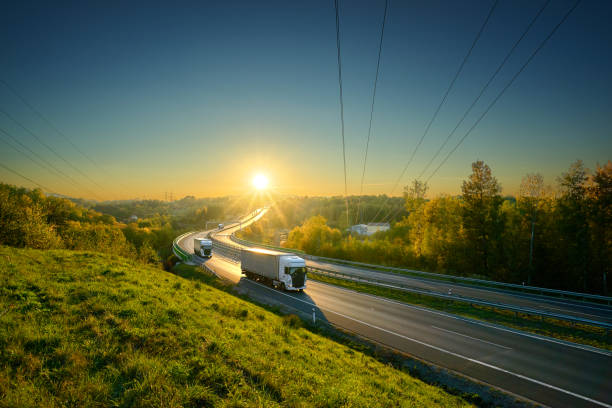tres camiones blanco en la autopista de asfalto en otoño paisaje en los rayos de la puesta del sol - riding autumn meadow land fotografías e imágenes de stock