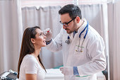 istock Doctor with serious facial expression taking sample with swab from the eye. 1126497419