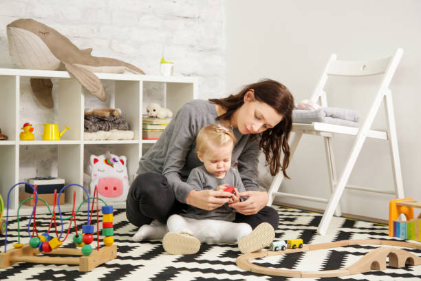 Mom and her baby girl spending time together in the nursery room stock photo