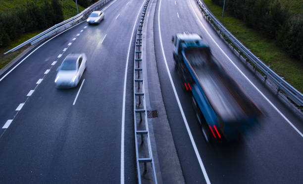 istock Trucks on a highway, motion blur, light trails. Night or evening shot of trucks doing transportation and logistics on a highway. 1126504022