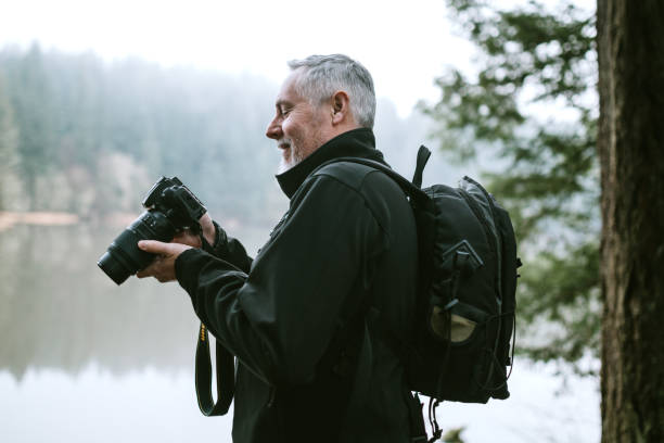 mature adult male photographer on nature hike - nature photographer imagens e fotografias de stock