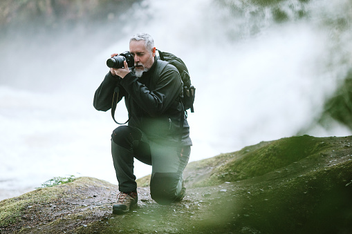 A man enjoys time outdoors in the Pacific Northwest, hiking beautiful forest trails and exploring rivers and waterfalls.  He documents his adventure with his digital camera.