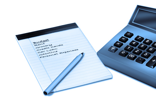 Budget writing on a notepad with pen and calculator in a blue hue on a white background