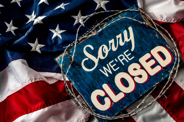 Government shutdown, political isolationism and economic slowdown in the United States of America concept with close up a sorry we're closed sign wrapped in barbwire on top of the American flag Government shutdown, political isolationism and economic slowdown in the United States of America concept with close up a sorry we're closed sign wrapped in barbwire on top of the American flag global populism stock pictures, royalty-free photos & images