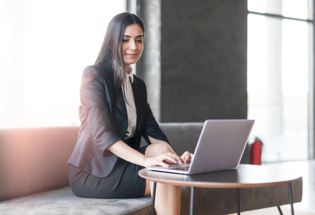istock Young woman sitting at hotel lobby, working on laptop 1126511593