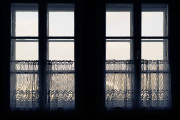 istock Looking out the old windows with half curtains from inside of dark room 1126511835