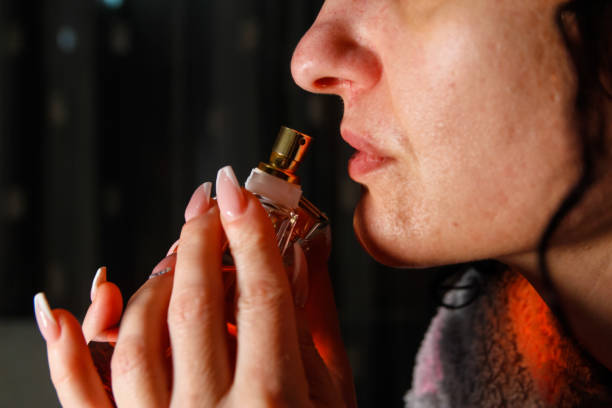 istock Young woman smelling perfume from a bottle 1126517495