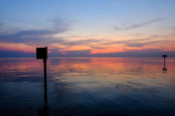 sunset scene with warning marking steel pole in the sea, twilight time. - commercial dock pier reef rock imagens e fotografias de stock