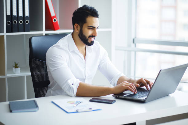 istock Smiling businessman using laptop at desk in office 1126522059