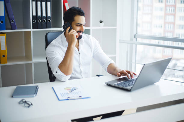 istock Smiling businessman using laptop at desk in office 1126522472