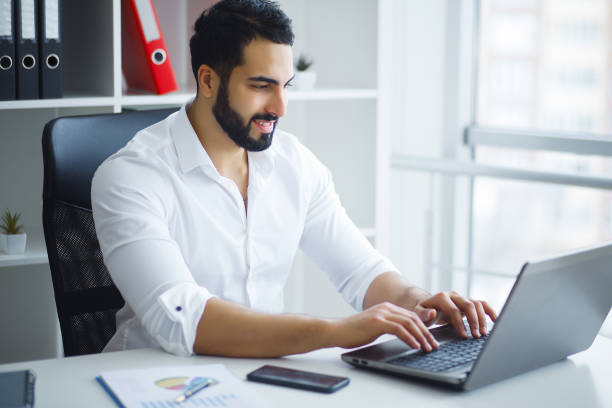 istock Smiling businessman using laptop at desk in office 1126522683