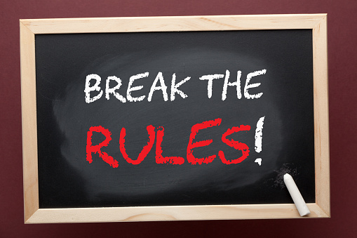 Break the rules written on blackboard by white chalk. Business concept.