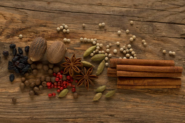 badiana (anís estrellado), cardamomo, secado agracejos, nuez moscada, limón, pimienta de jamaica (guisantes), pimiento rojo, pimienta blanca y canela en una superficie de madera natural. - badian fotografías e imágenes de stock