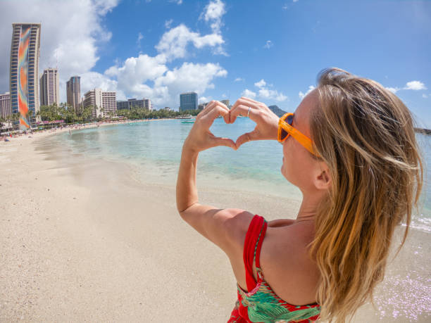 istock Young woman on Waikiki beach in Hawaii making a heart shape finger frame 1126529892
