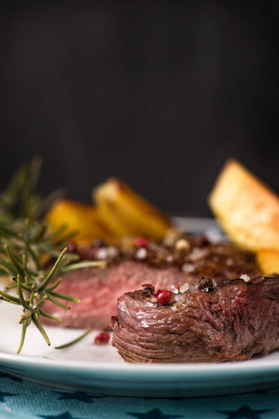 istock Beef steak with fried potatoes in slices on a white rectangular plate in a restaurant. 1126531385