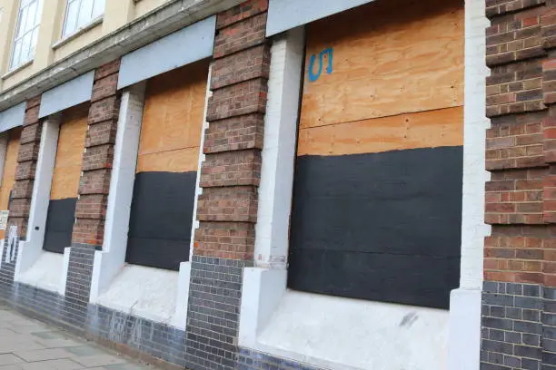 London building awaiting construction with boarded-up windows and warning signs