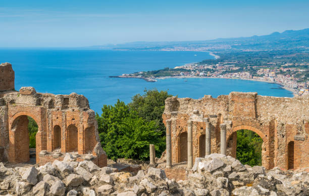 ruínas do teatro do grego antigo em taormina com o litoral siciliano. província de messina, sicília, sul da itália. - sicily taormina mt etna italy - fotografias e filmes do acervo